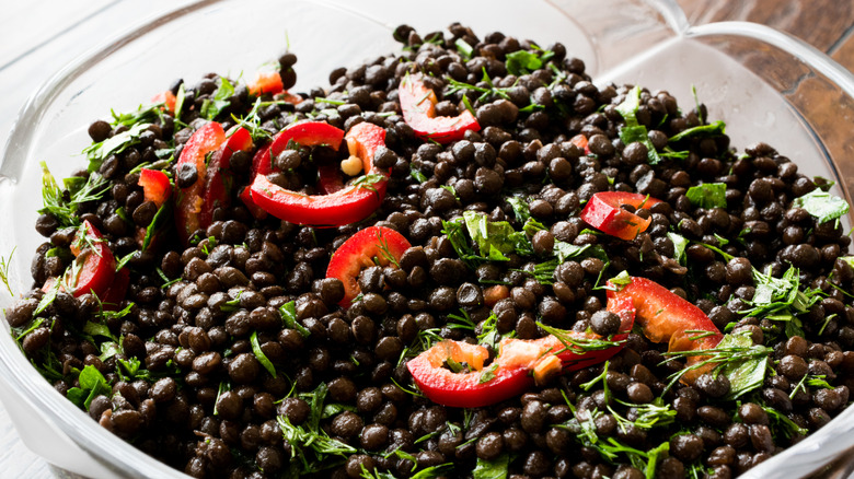 Bowl of black lentils with red bell peppers and parsley