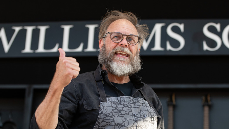 Alton Brown with a beard and glasses holding a thumbs up