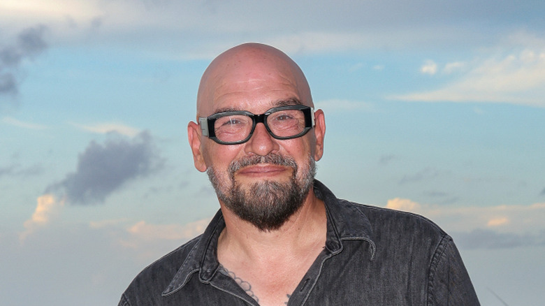 Michael Symon wearing glasses and smiling against a blue sky