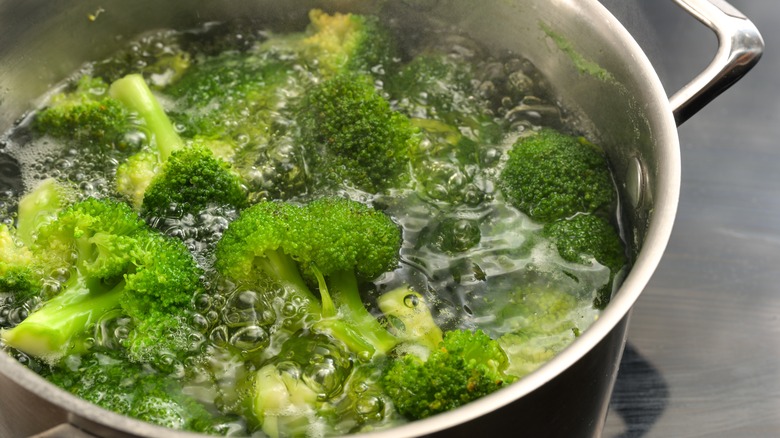 brown hands chopping broccoli