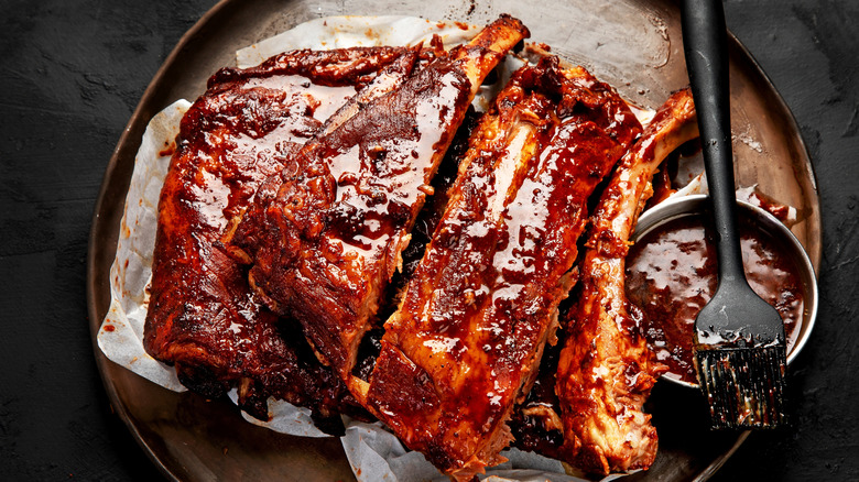 Barbecue ribs on a wooden plate with sauce.