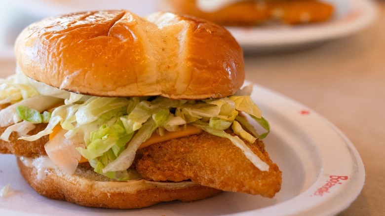 Bojangles' fish sandwich with pickles, tomatoes, and lettuce, nestled in a soft bun.