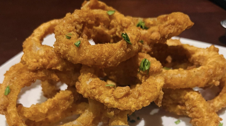 An order of onion rings served with a side of ranch from Firebirds Wood Fired Grill