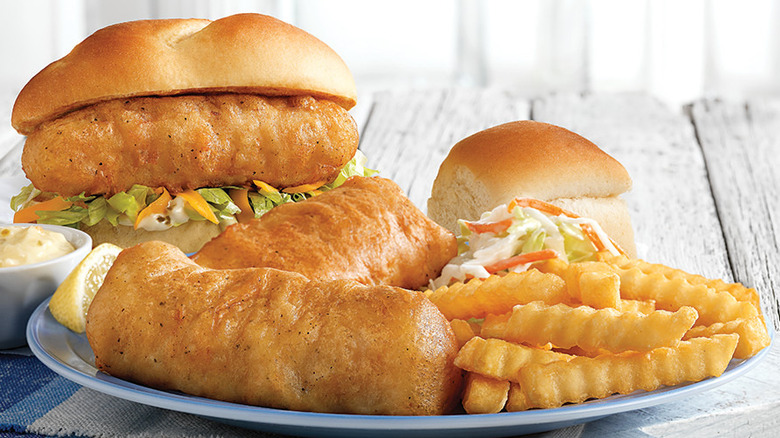 Cod dinner, fries, coleslaw, and sandwich on a plate.