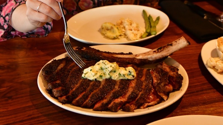 Sliced tomahawk steak on platter on table at Del Frisco's.