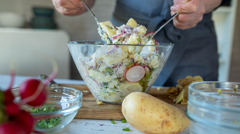 Someone prepares a potato salad.