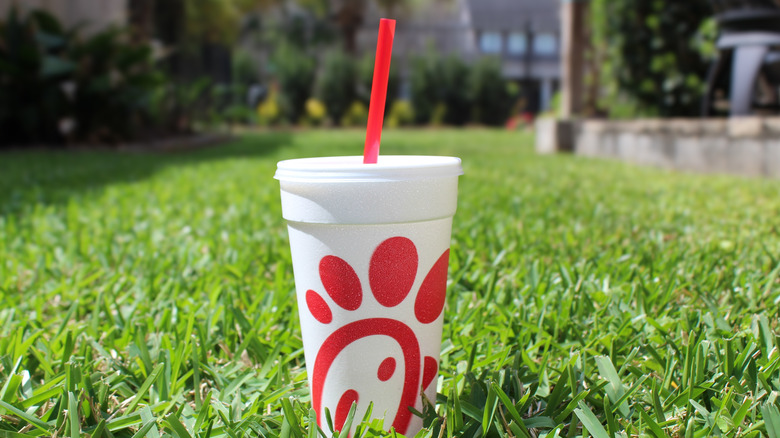 Chick-fil-A cup with straw on grass.