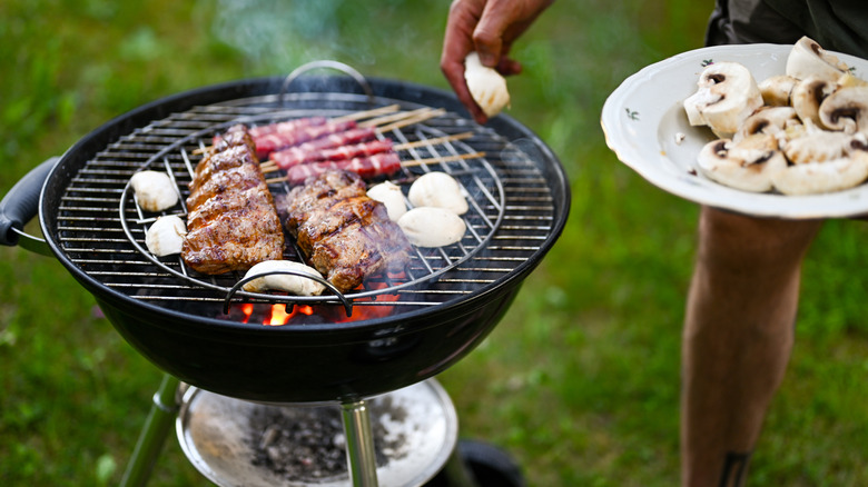 Steak, mushrooms, and kebabs cooking over charcoal grill outdoors