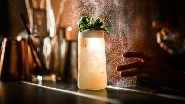 A cocktail with mint on top sits on a bar