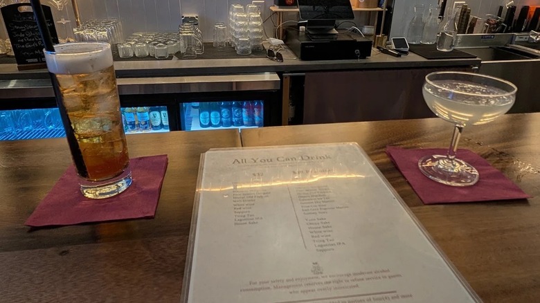 A bar menu sits atop the bar at Huuma in New York City alongside two cocktails