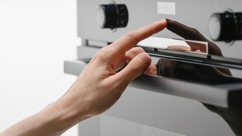 Hand adjusting the temperature on an oven
