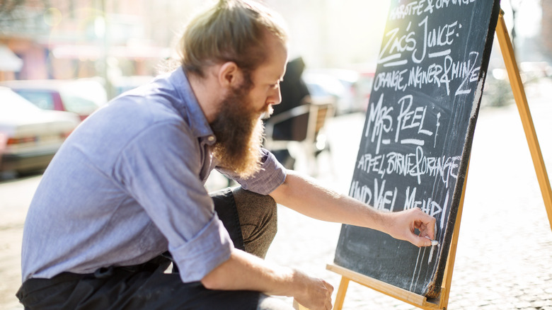 Waiter writing specials on a chalkboard