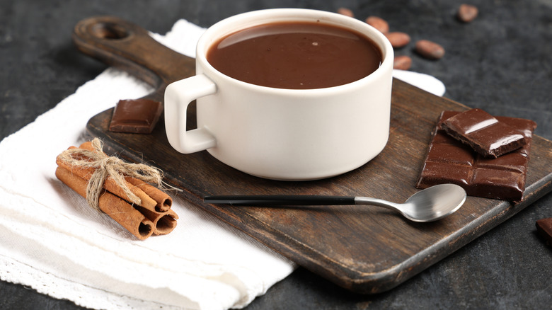 Cup of hot chocolate on board with cinnamon sticks