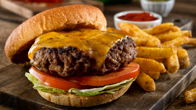 Cheeseburger with fries served on a wooden plank