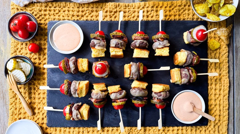 Cheeseburger skewers on slate board with dipping sauce and chips