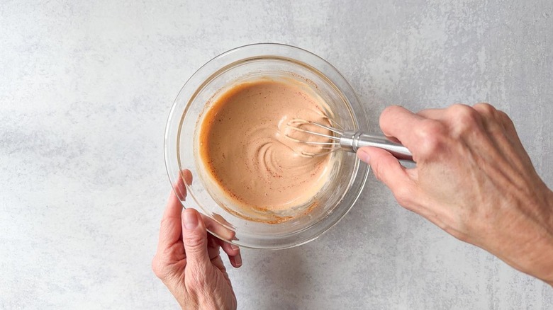 Whisking together burger sauce ingredients in glass bowl