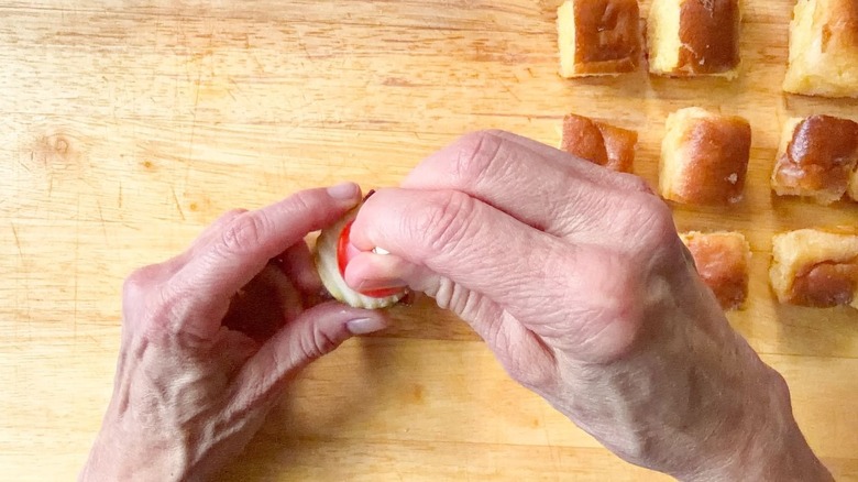 Skewering a mini cheeseburger on cutting board