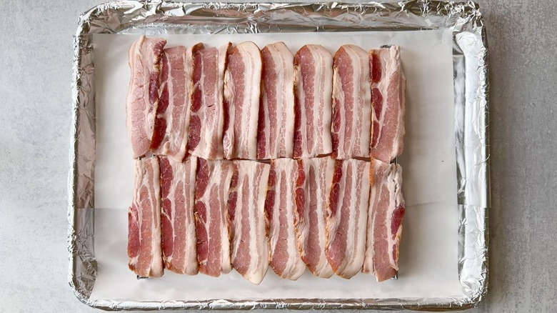 Bacon strips on rack over foil and parchment-lined baking sheet