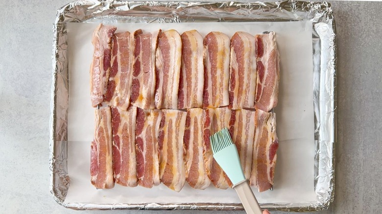 Brushing maple syrup onto bacon strips on rack