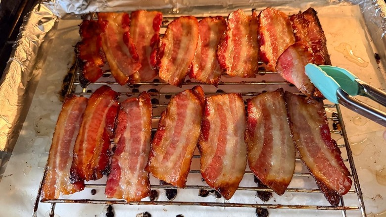 Flipping maple glazed oven on rack over baking sheet in oven using tongs