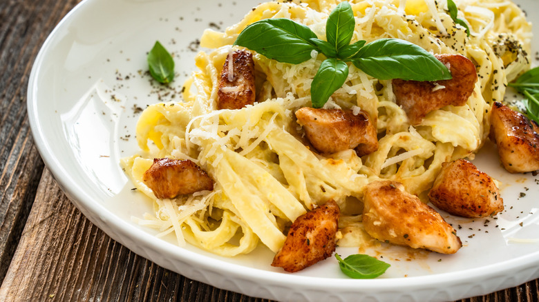 White plate with fettuccine Alfredo with chicken and basil