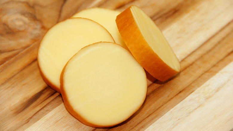 provolone cheese rounds on wooden cutting board