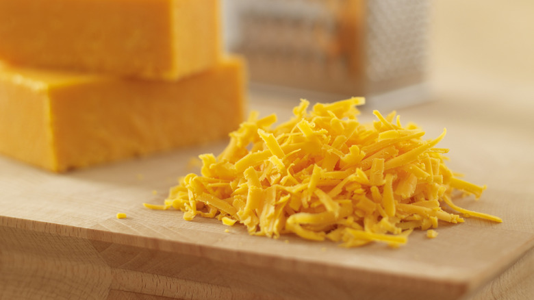 grated cheddar with blocks and box grater in background