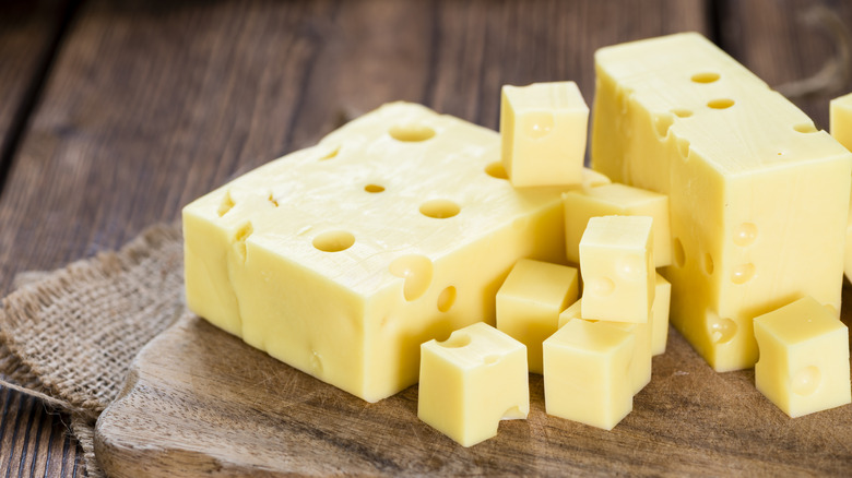 Swiss cheese with large holes on wooden board
