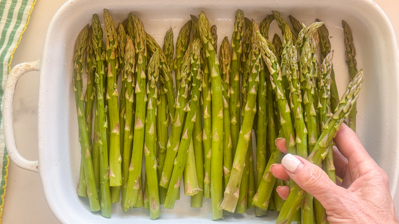 hand laying asparagus in dish