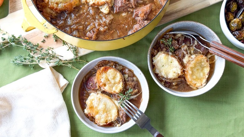 Cheesy French onion pot roast in serving bowls with fresh thyme and forks