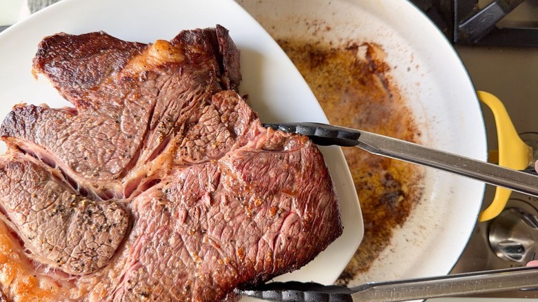 Seared boneless beef chuck roast on plate with tongs