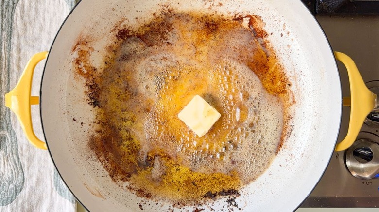 Olive oil and butter melting in large pot with browned bits