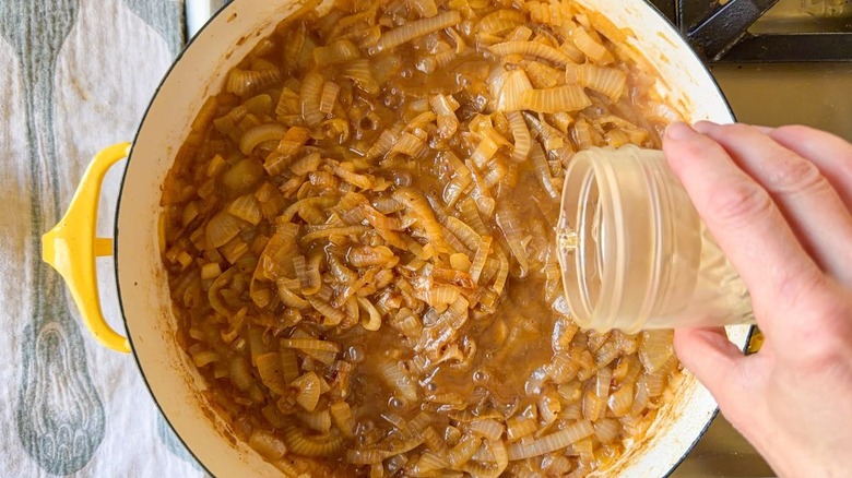 Adding white wine to caramelized onions in large pot on stovetop