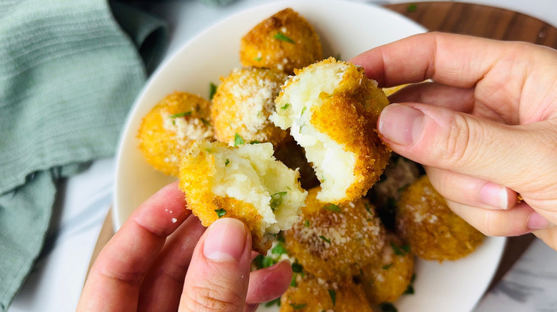 Hands pulling apart fried mashed potato ball