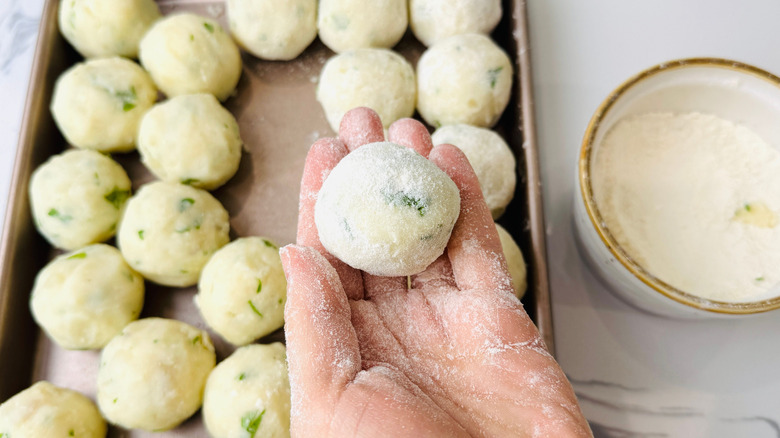 Hand holding flour coated mashed potato ball