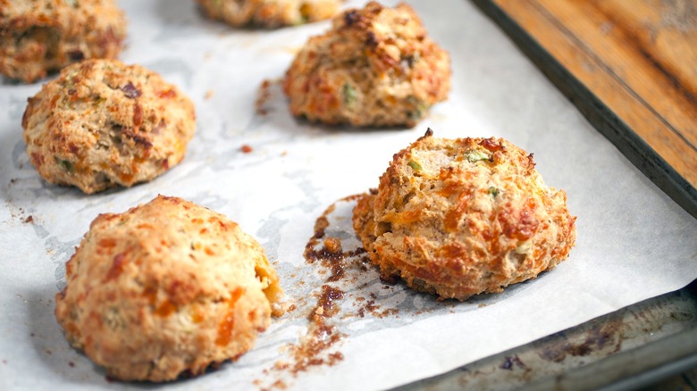 Freshly baked biscuits with cheese and green onions on a parchment-lined sheet pan
