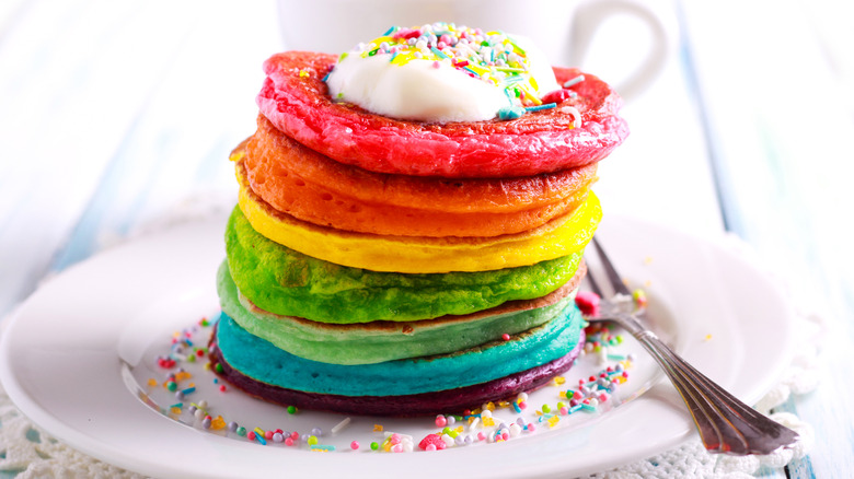 Stack of rainbow-colored pancakes on plate