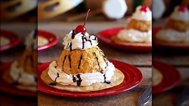 Fried ice cream topped with chocolate sauce, whipped cream, and a cherry on top of tortilla.