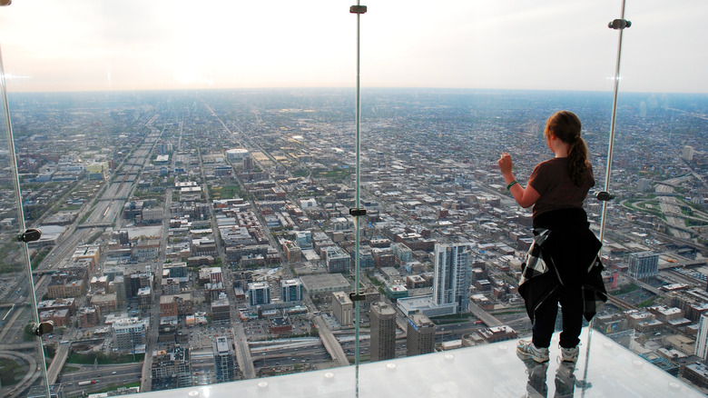 A person looking out the Chicago skyline through floor-to-ceiling glass windows.