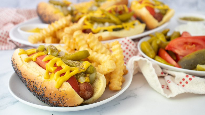Side shot of several Chicago-style hot dogs and toppings