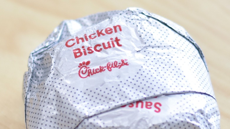 The exterior wrapper of a Chick-fil-A chicken biscuit sandwich on a wooden table