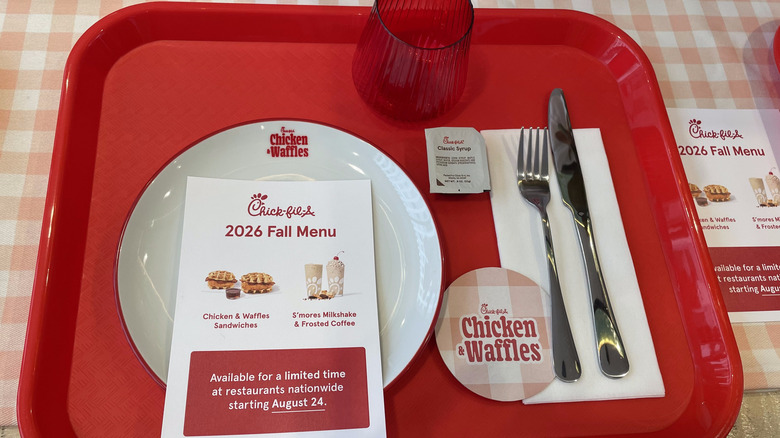 A red plastic tray holds a plate, fork, knife, red cup, and fall menu marketing sheet from Chick-fil-A.