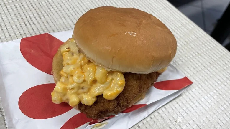 A Chick-fil-A chicken sandwich filled with Chick-fil-A's mac and cheese sitting on a sandwich wrapper
