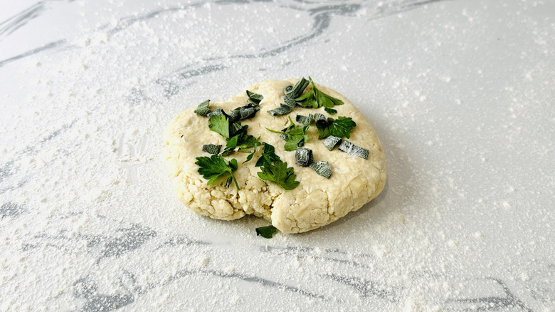 flattened mound of dough with herbs piled on top