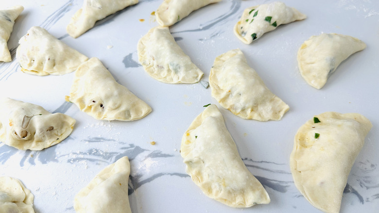 small semicircular unbaked pies on a kitchen counter