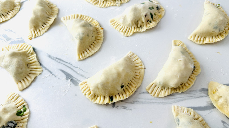 small semicircular unbaked pies on a kitchen counter