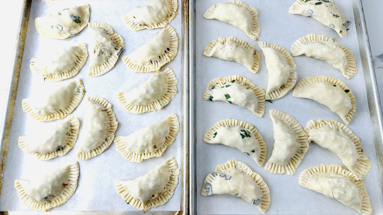 small semicircular unbaked pies on two baking sheets