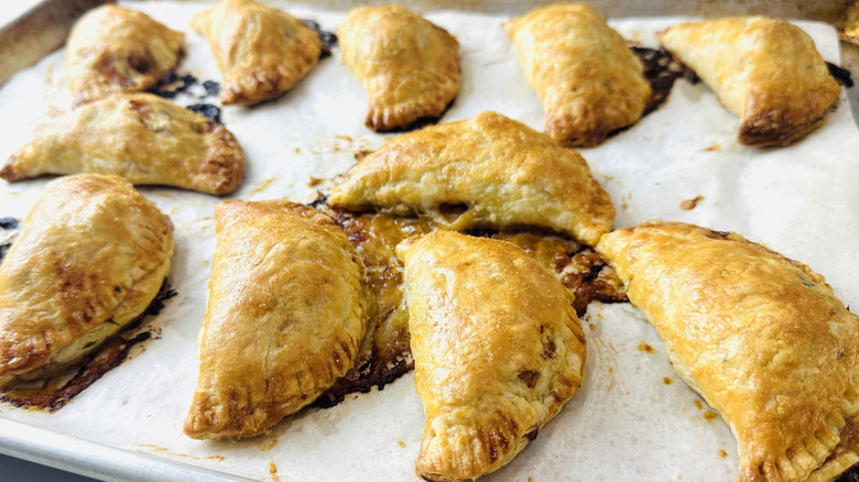 small semicircular pies on a baking sheet