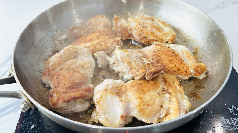 partially-cooked chicken in a frying pan