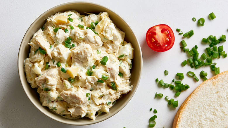A bowl of creamy chicken salad topped with fresh chopped green onions